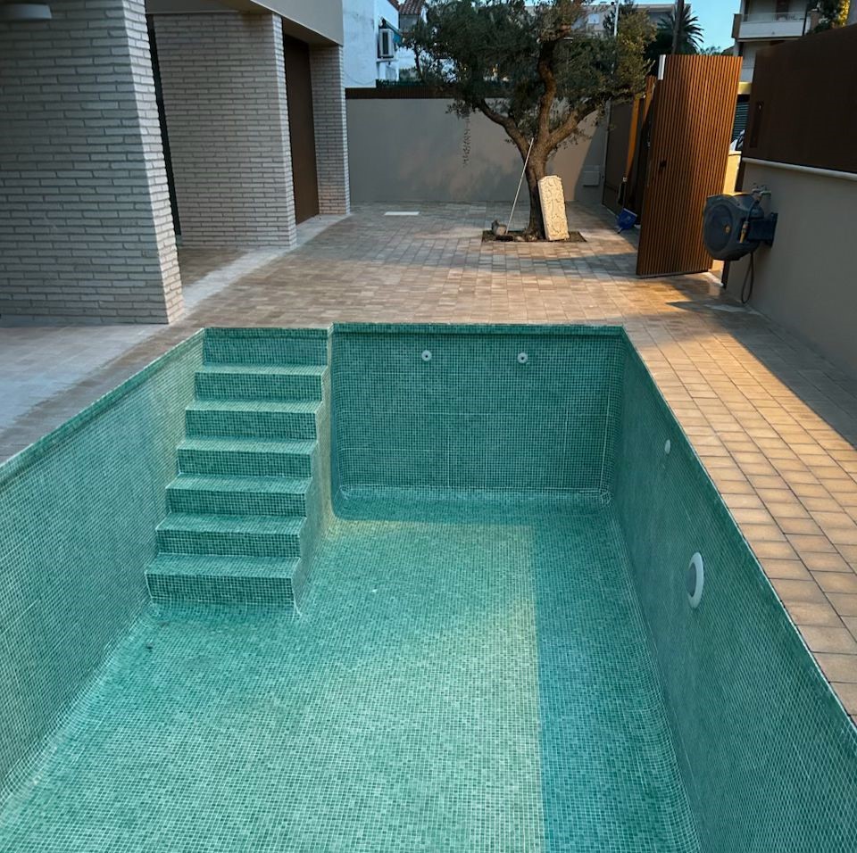 Piscina de obra nueva con acabados modernos en jardín de vivienda en Tarragona. Servicio de construcción de piscinas de calidad